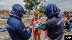 En esta foto de archivo tomada el 21 de agosto de 2020, funcionarios de migración colombianos revisan el documento de un venezolano que regresa a casa con un niño pequeño en el Puente Internacional Simón Bolívar, Cúcuta, Colombia, frontera con Venezuela. 