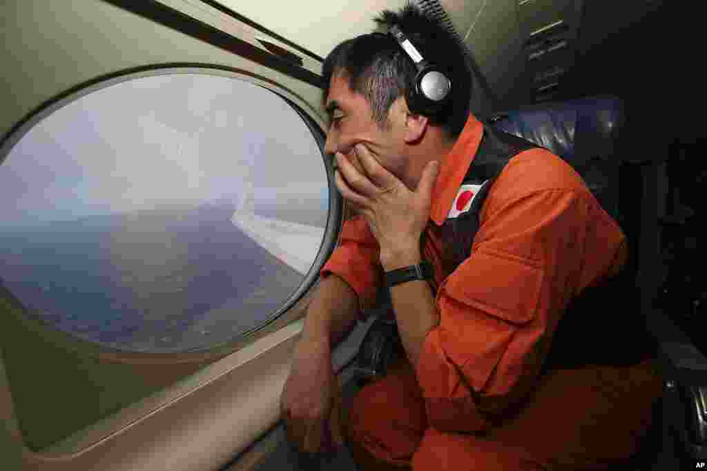 Koji Kubota of the Japan Coast Guard keeps watch while flying in the search zone for debris from flight MH370, April 1, 2014.