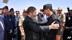An image released by the Egyptian Presidency shows Mohammed Morsi (C) embracing an Egyptian policeman after he was freed from captivity, in Cairo, May 22, 2013. 