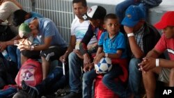 FILE - A Honduran boy holds his soccer ball after receiving a processing bracelet from a worker of the Mexican Migration Institute or Instituto Mexicano de Migracion, as he enters Mexico from Guatemala, near Ciudad Hidalgo, Chiapas State, Mexico, Jan. 18, 2019.