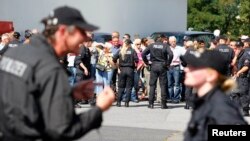 People stand outside during a visit of German Chancellor Angela Merkel to an asylum seekers accomodation facility in the eastern German town of Heidenau near Dresden, August 26, 2015 where last week more than 30 police were injured in clashes, when a mob 