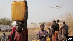 In this photo taken Wednesday, Feb. 26, 2014, a displaced South Sudanese woman carries a plastic jerry can with water in the United Nations camp that has become home to thousands of displaced people in Malakal, South Sudan. (AP Photo/Ilya Gridneff)