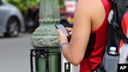 In this Oct. 25, 2017, photo a man uses his cellphone before crossing a street in Honolulu. A new Honolulu ordinance allows police officers to issue tickets to pedestrians caught looking at a cellphone or electronic device while crossing a city street.