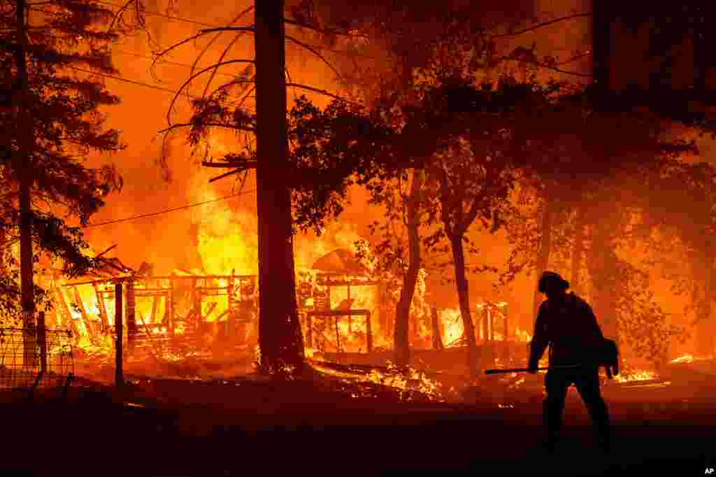 A firefighter passes a burning home as the Dixie Fire flares in Plumas County, Calif., July 24, 2021.