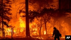 A firefighter passes a burning home as the Dixie Fire flares in Plumas County, Calif., July 24, 2021.