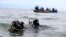 Members of the Uganda Police Marine Unit participate in rescue efforts after a boat carrying mostly Congolese refugees capsized in Lake Albert southwest of Uganda's capital, Kampala, March 23, 2014.