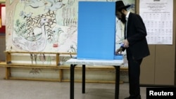 An ultra-Orthodox Jewish man stands near a booth at a polling station in the West Bank Jewish settlement of Kochav Ya'acov, north of Jerusalem, January 22, 2013. 