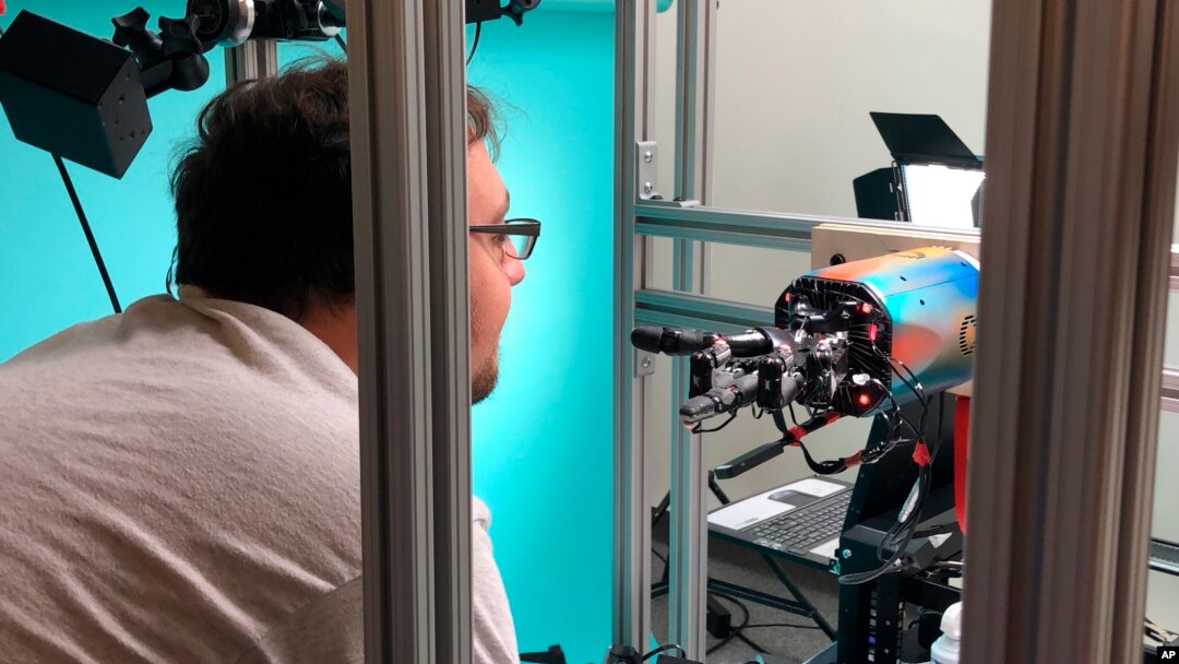OpenAI researcher Jonas Schneider examines the research lab’s robotic hand in San Francisco, July 26, 2018.