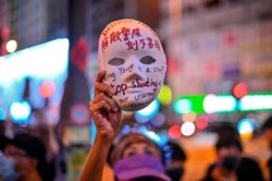 A woman holds a mask with slogans written on it as protesters gather outside Mong Kok police station in Hong Kong, Oct. 5, 2019, a day after the city's leader outlawed face coverings at protests invoking colonial-era emergency powers.