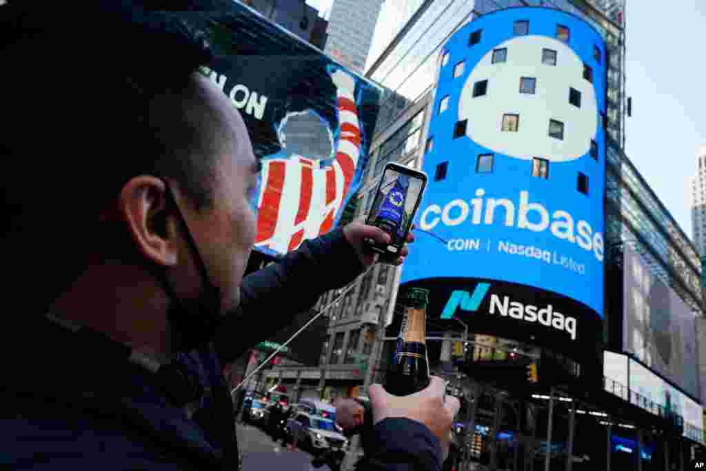  Coinbase employee Daniel Huynh takes a photo of the Nasdaq MarketSite in New York&#39;s Times Square. Wall Street will be focused on Coinbase with the digital currency exchange becoming a publicly traded company.