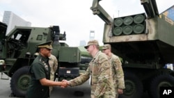 FILE - Philippine military chief Gen. Romeo Brawner Jr. left, greets US soldiers beside a HIMARS rocket launcher on display during the Asian Defense and Security Exhibition on Sept. 25, 2024, in Manila, Philippines. 