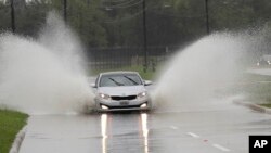 A car drives through floodwaters from Tropical Depression Imelda, Sept. 18, 2019, in Houston. 