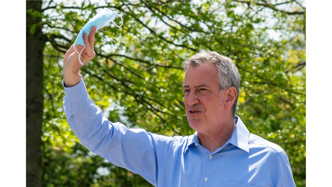 FILE PHOTO: New York City Mayor Bill De Blasio speaks to people as he gives away face masks for using in public spaces to prevent the spread of coronavirus disease (COVID-19), May 16, 2020.