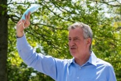 FILE PHOTO: New York City Mayor Bill De Blasio speaks to people as he gives away face masks for using in public spaces to prevent the spread of coronavirus disease (COVID-19), May 16, 2020.