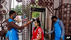 An Indian man checks the temperature of a devotee on the eve of the annual Rath Yatra, or Chariot procession of Lord Jagannath, in Ahmedabad, India, July 11, 2021.