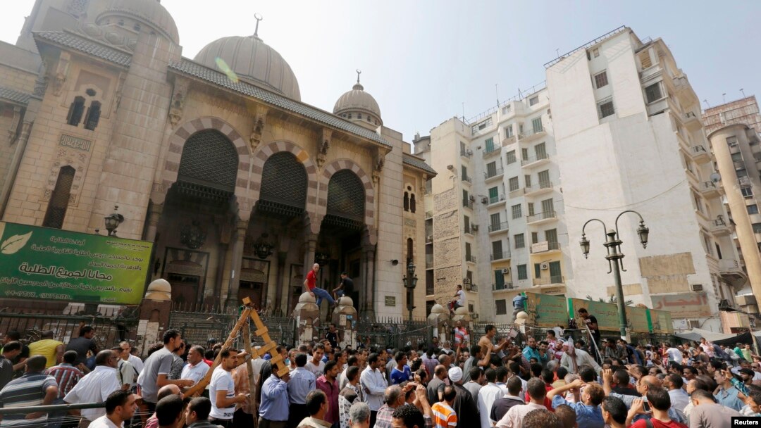 Pemrotes anti-Morsi dan polisi anti huru-hara berkumpul di luar masjid al-Fatah di Lapangan Ramses, Kairo (17/8).