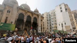 Pemrotes anti-Morsi dan polisi anti huru-hara berkumpul di luar masjid al-Fatah di Lapangan Ramses, Kairo (17/8).