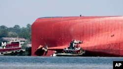 Rescuers work near the stern of the vessel Golden Ray as it lays on its side near the Moran tug boat Dorothy Moran, Sept. 9, 2019, in Jekyll Island, Georgia.