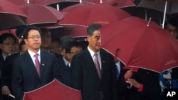 Hong Kong Chief Executive Leung Chun-ying, center, and Zhang Xiaoming, left, director of the Liaison Office of the Central People's Government in Hong Kong attend a flag raising ceremony, Oct. 1, 2016.