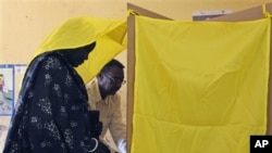 A member of the polling staff helps a Southern Sudanese woman to vote at a polling center in the suburb of al-Jereif in Khartoum, Sudan, 14 Jan 2011