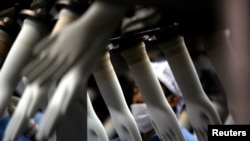 FILE - A worker collects rubber gloves at a factory outside Kuala Lumpur, Malaysia.