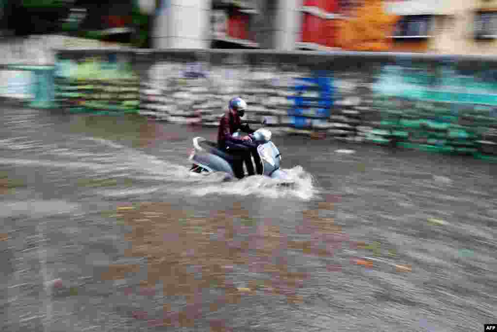 A man rides a scooter through a waterlogged street following heavy rains from Cyclone Tauktae in Mumbai, India.