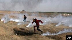 Demonstran Palestina berlari untuk menghindari tembakan gas air mata pasukan Israel pada aksi protes di Gaza dekat perbatasan Israel (13/4). 