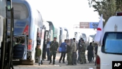 Les forces gouvernementales syriennes supervisent l'évacuation par bus des combattants rebelles et de leurs familles dans la région orientale de la Ghouta près de Damas, Syrie, 28 mars 2018.. 