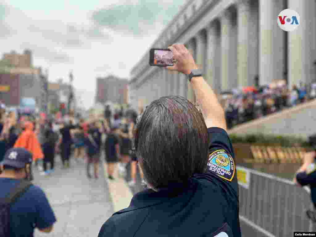 Polic&#237;a tomando una imagen de las protestas con su celular. Foto: Celia Mendoza-VOA 
