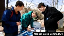 In this March 20, 2008, photo young student Obama volunteers Mike Stratta, left, and Christo Logan, right, stand with University of Pennsylvania employee Dave Munson, 45, as he fills up a voter registration form on University of Pennsylvania campus, in Philadelphia. (AP Photo)