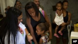 Tais da Silva Almeida tranquiliza a su hija de cinco años, mientras una trabajadora de salud se prepara para vacunarla contra la fiebre amarilla. Brasil, Marzo 17, 2017. 