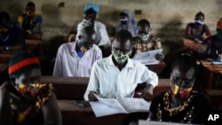 FILE - A trainee reads a handbook on coronavirus prevention, at a training session for community health workers conducted by the national NGO Health Link in Gumbo, on the outskirts of Juba, South Sudan, Aug. 18, 2020.