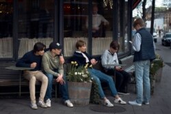 FILE - Young people hang out outside a restaurant in Stockholm, Sweden, April 8, 2020.