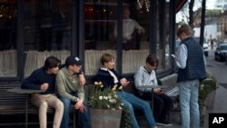 FILE - Young people hang out outside a restaurant in Stockholm, Sweden, April 8, 2020.