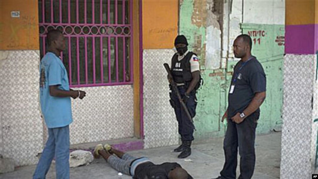 Police officers arrest a man outside the National Penitentiary during a prisoners' uprising in downtown Port-au-Prince, Haiti, 17 Oct 2010