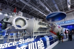 In this Nov. 7, 2018, photo, visitors look at a life-size model of the Tianhe core module of China's next space station at the Airshow China in Zhuhai in southern China's Guangdong Province.