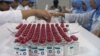 Lab workers in the Bandung BioFarma facility in Indonesia examine vials that have vaccine vial monitor technology incorporated into their labels, in Bandung, Indonesia, February 2017. (U. Kartoglu/PATH)