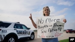 Seorang warga bernama Mary Ann Foley membawa poster berisi seruan protes untuk pihak berwenang agar segera mengambil tindakan untuk menhentikan penembakan massal ketika ia mengunjungi acara mengenang korban penembakan di Allen, Texas, pada 7 Mei 2023. (Foto: AP/LM Otero)
