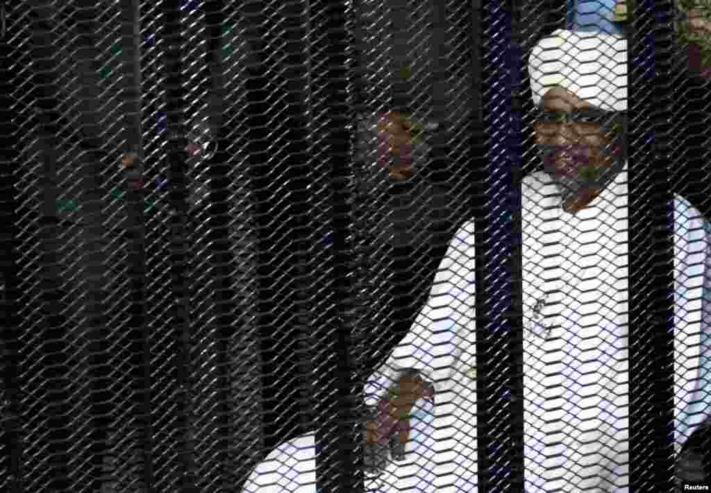 Sudan&#39;s former president Omar Hassan al-Bashir sits guarded inside a cage at the courthouse where he is facing corruption charges, in Khartoum, Aug. 19, 2019.