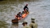 Migrantes que se dirigen al norte llegan a Lajas Blancas, donde un agente de la policía fronteriza panameña se encuentra en la orilla del río Chucunaque, en la provincia de Darién, Panamá, el 6 de octubre de 2023, después de cruzar caminando el Tapón del Darién desde Colombia.