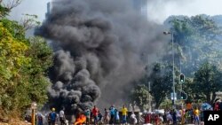 FILE - This July 12, 2021 photo shows looters outside a shopping center alongside a burning barricade in Durban. Former president Jacob Zuma's incarceration for contempt of court sparked off the worst violence South Africa has seen since the nation achieved democracy in 1994.