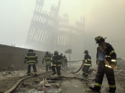 FILE - Firefighters work beneath the destroyed mullions, the vertical struts which once faced the soaring outer walls of the World Trade Center towers, after a terrorist attack on the twin towers in New York, Sept. 11, 2001.