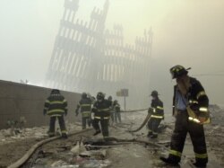 FILE - Firefighters work beneath the destroyed mullions, the vertical struts which once faced the soaring outer walls of the World Trade Center towers, after a terrorist attack on the twin towers in New York, Sept. 11, 2001.