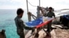 Marinir Filipina melipat bendera nasional Filipina di Second Thomas Shoal yang disengketakan, bagian dari Kepulauan Spratly di Laut Cina Selatan. (Foto: REUTERS/Erik De Castro)