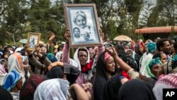 FILE - Relatives mourn as they lift portraits of family members they lost in the collapse of a mountain of trash at a garbage dump, during a funeral service held at Gebrekristos church in Addis Ababa, Ethiopia, March 13, 2017.