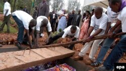 Des volontaires déposent dans un caveau les restes des victimes du génocide de 1994, à Murambi, dans l'Est du Rwanda, 07 avril 2005. EPA / RICKY GARE