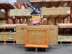 A shopper stands with a dolly of plywood at The Home Depot ahead of Hurricane Dorian on Aug. 29, 2019, in Pembroke Pines, Fla.