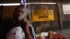 FILE - An unidentified man smoke Marijuana at the New Afrika Shrine next to a no drugs sign in Lagos, Nigeria.