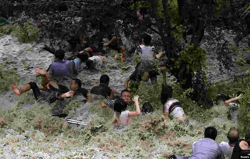 Orang-orang berjuang melawan gelombang&nbsp; pasang yang menabrak penghalang di tepi sungai Qiantang di Provinsi Haining, Zhejiang, akibat serangan topan Trami di Cina Timur.