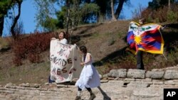 Protesters displaying a Tibetan flag and a banner reading &quot;No genocide games&quot; enter the grounds during the lighting of the Olympic flame at Ancient Olympia site, birthplace of the ancient Olympics in southwestern Greece.